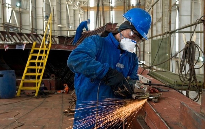 person using grinder in shipyard