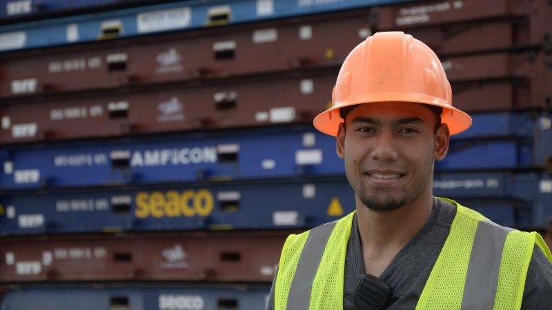 Man in a hard hat standing in front of cargo equipment
