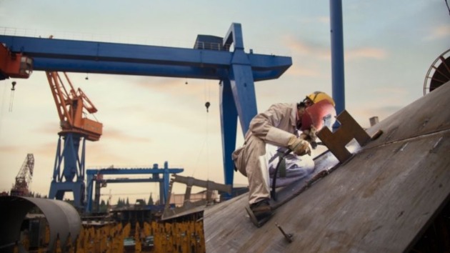 Worker welding on the side of a ship