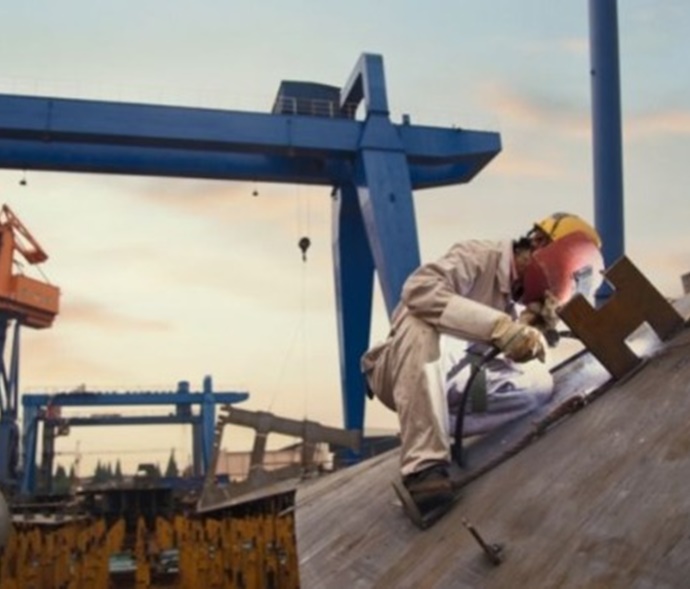 Worker welding on the side of a ship