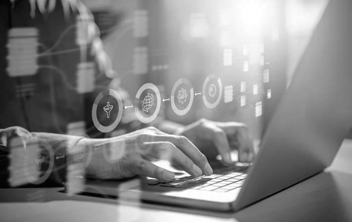Fingers typing on a laptop with log on icons floating above