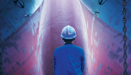 Worker in hard hat standing in front of ship