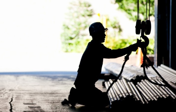 worker securing pipes in a sling